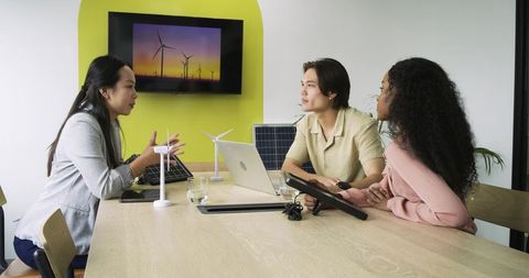 Diverse coworkers discussing wind energy project in modern office