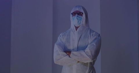 Male professional wearing full ppe suit, mask and goggles, arms crossed in sterile lab