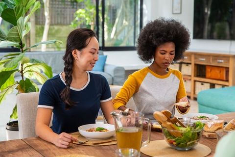 Diverse Friends Enjoying Pasta and Salad at Dining Table
