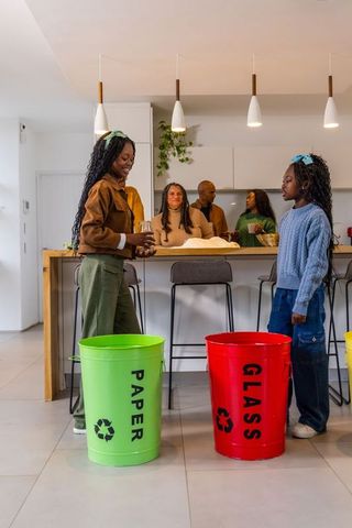 African american girls sorting recycling in modern kitchen holding glass with family