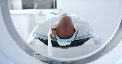 African american male undergoing ct scan with head immobilizer in hospital radiology suite