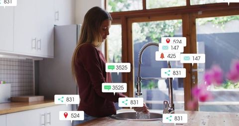 Woman Engaging with Notifications While Washing Hands at Kitchen Sink