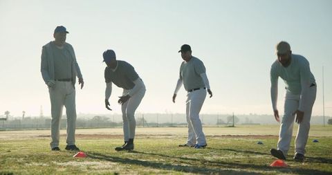 Baseball Team Practicing Agility Drills at Sunrise with Coach Guiding Players Using Cones