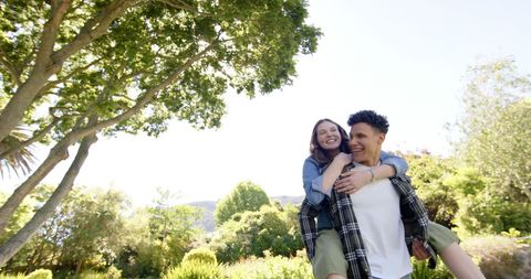 Happy Couple Enjoying Piggyback Ride in Sunny Park Setting
