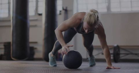 Strong Woman Executing Plank Push-Up with Medicine Ball