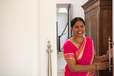 Smiling woman in pink-gold saree opening wardrobe door
