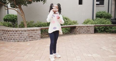 Joyful Child Blowing Bubbles in Courtyard