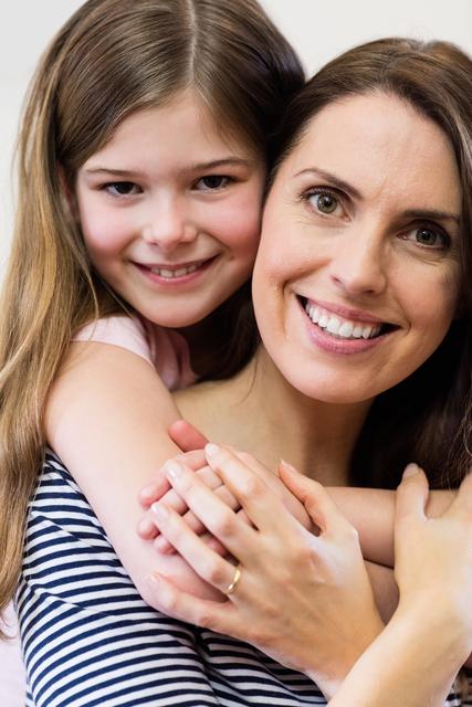 Mother and daughter embracing and smiling at home, showcasing family love and bonding. Ideal for use in family-oriented advertisements, parenting blogs, and lifestyle articles.