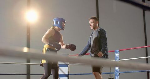 Boxer Sparring with Coach in Ring Under Spotlight — Male Trainer Guiding Athlete During Training