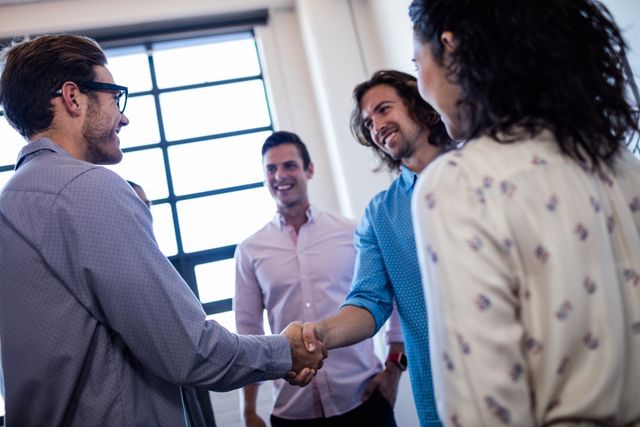 Group of young hipsters in casual attire interacting and handshaking in a modern office. Ideal for themes related to teamwork, collaboration, business meetings, professional networking, and modern workplace environments. Useful for illustrating concepts of friendly communication, startup culture, and young professionals.