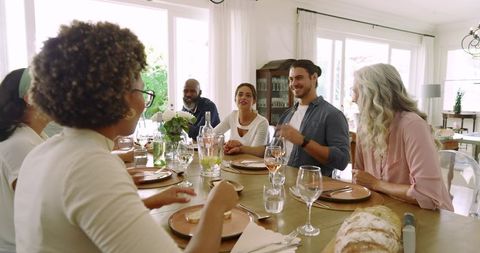 Friends laughing and conversing around dining table during wedding celebration