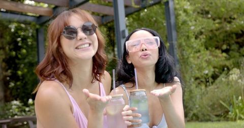 Women enjoying refreshing drinks by poolside in summertime
