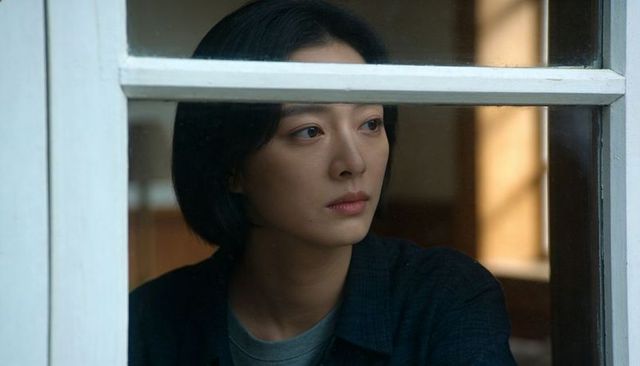 Pensive asian woman looking through window with soft mood lighting and bokeh