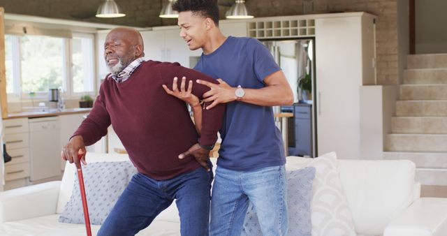 Young Man Assisting Elderly Father with Back Pain at Home - Download Free Stock Images Pikwizard.com