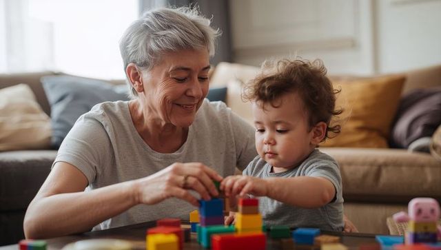 Grandmother guiding toddler stacking colorful blocks, intergenerational bonding at home