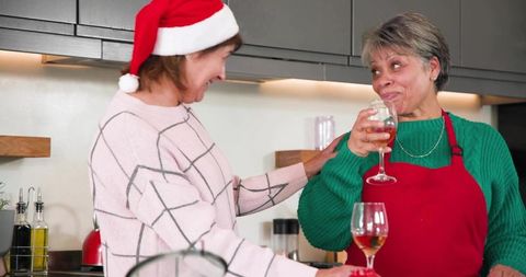 Sharing holiday toast in cozy home kitchen: mature women celebrating friendship
