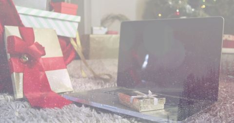 Holiday laptop amid festive gift boxes on carpeted floor