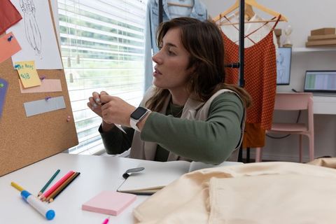 Fashion designer pinning fabric swatch on corkboard in home studio workspace
