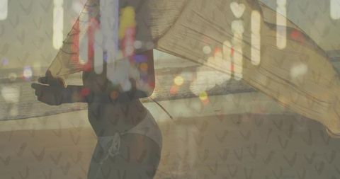 Raising sheer scarf on sunset beach backlit silhouette with translucent wrap and lens flare