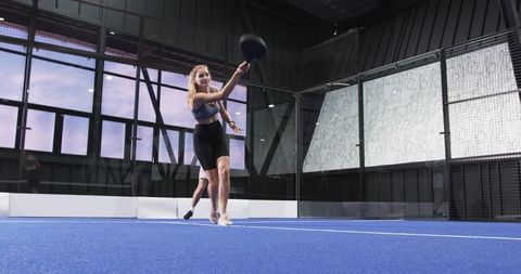 Athlete Engaged in Padel Game on Indoor Court with Glass Walls