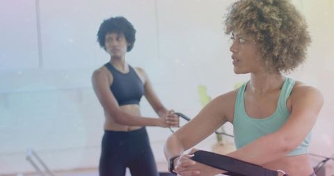 Two women practicing pilates reformer workout in bright studio for core strength