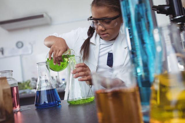 Elementary student pouring green chemical in flask on desk at science laboratory