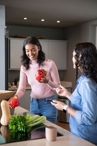 Diverse friends unpacking fresh produce in modern kitchen