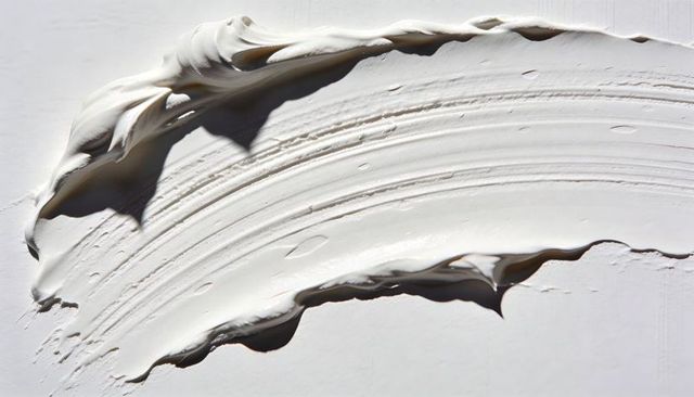Thick white paint smear creating textured crescent with palette knife ridges and gloss