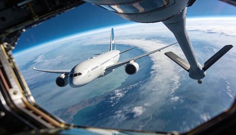 Widebody airliner approaching aerial refueling boom over coastal horizon and ocean
