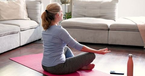 Senior Woman Meditating on Yoga Mat in Peaceful Living Room
