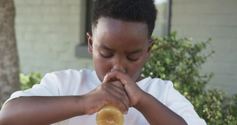 Young boy drinking juice from plastic bottle on suburban porch during sunny afternoon