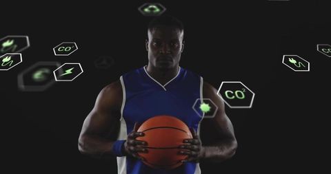 Focused basketball player holding ball wearing blue jersey with green energy icons