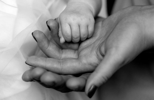 Baby hand gently holding parent's hand in black and white. Ideal for themes involving family, bonding, parental love, and child care. This close-up symbolizes nurturing, support, and intimacy in parent-child relationships. Suitable for articles, blogs, or advertisements focusing on parenting, family connections, and emotional support.