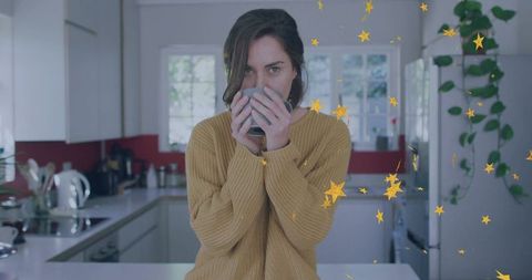 Cozy morning woman holding mug at kitchen island in mustard sweater with gold star overlay