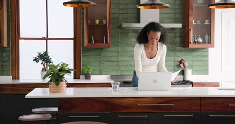 Woman Working on Laptop in Stylish Kitchen with Green Accents