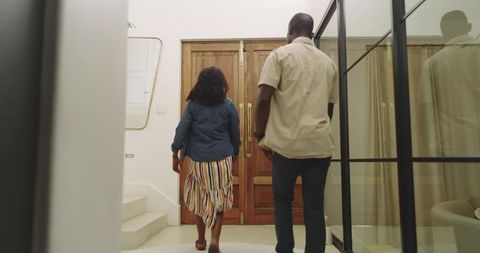 African American Couple Walking Through Modern Home Entry Toward Wooden Double Doors