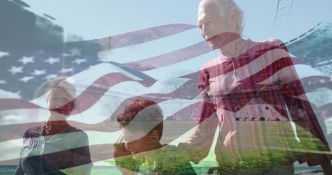 Senior Couple Walking with Grandchildren on Beach under American Flag
