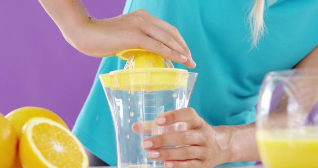 Close-up on hands squeezing fresh oranges with a juicer, perfect for illustrations of healthy lifestyle, fresh food preparations, and morning routines. Ideal for wellness blogs, recipes, health and diet articles, and promotional materials related to fresh, homemade beverages.