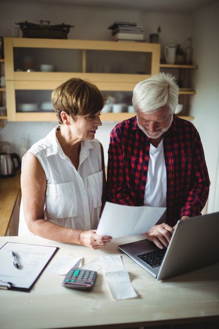 Senior couple paying bills online on laptop at home