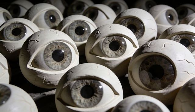 Prosthetic eye spheres displaying textured irises and cracked sclera in dim studio