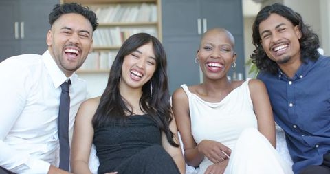 Diverse young professionals laughing on sofa during casual corporate lounge gathering