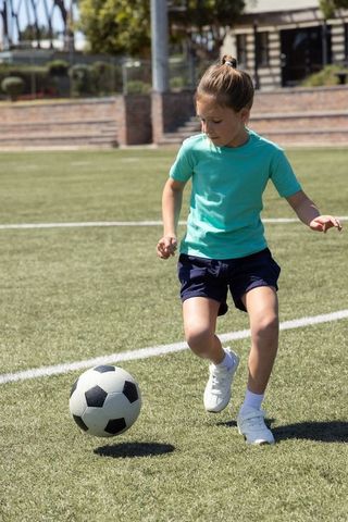 Girl dribbling soccer ball on turf field practicing skills and building confidence youth sports