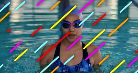 Female swimmer standing in pool wearing goggles and cap with neon diagonal streaks