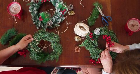 Two people crafting festive christmas wreaths at home