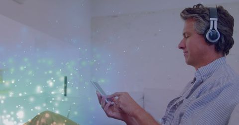 Man relaxing with headphones and smartphone amidst digital sparks