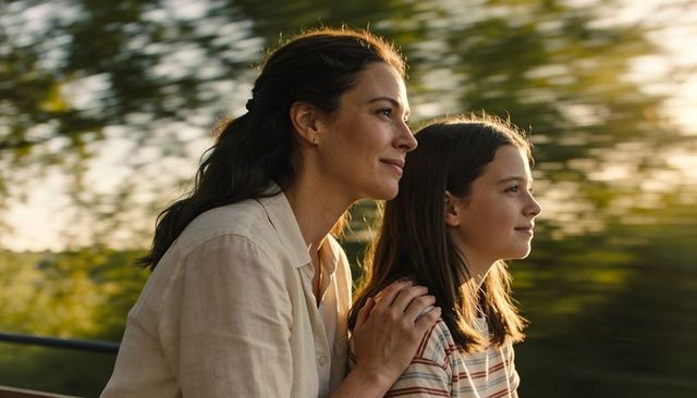 Mother and daughter enjoying sunlit train ride at golden hour, looking ahead