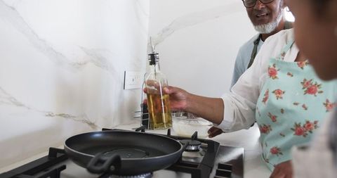 Man Preparing Meal in Modern Home Kitchen Setting, Pouring Cooking Oil