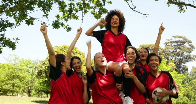 Women's soccer team celebrating victory outdoors, surrounded by nature. Teammates are cheering, expressing joy and happiness. Perfect for themes related to sports, victory, teamwork, unity, and female empowerment. Can be used in sports promotions, motivational campaigns, team-building activities, and youth sports programs.