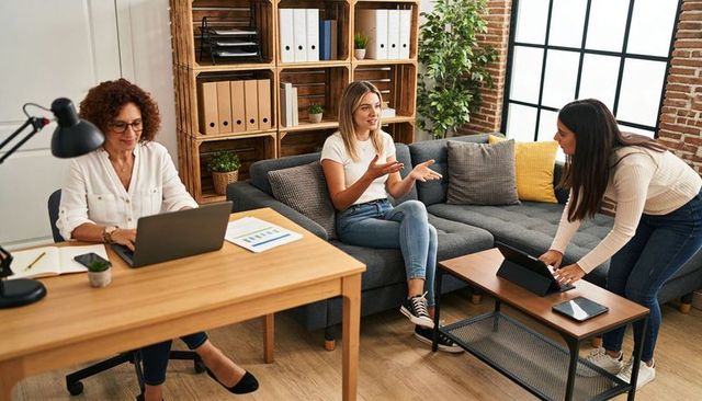 Women collaborating in modern office lounge using laptop and tablet for team planning