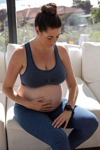 Pregnant Woman Meditating on Sofa in Blue Activewear